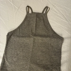 Ny grå linnetopp från NLY TREND XS - Snygg grå linnetopp från NLY TREND i storlek XS. Toppen har smala axelband och en hög halsringning. Ej använt 