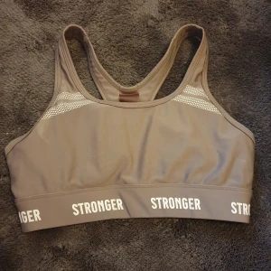 Sport-bh från Stronger - Sport bh från stronger med bred resår och logga runt om. Snygg racerback och diskreta vita detaljer framtill. Perfekt för träning och ger maximal komfort. Tror det är storlek S men passar nog Xs också. För liten för mig. 