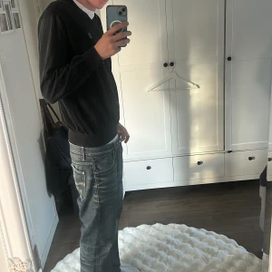  V-rngad tröja från Henri Lloyd - Svart v-ringad tröja från Henri Lloyd med diskret logga på bröstet. Tröjan har lång ärm och är tillverkad i mjuk bomull, perfekt för en clean och stilren look. Passformen är normal och den funkar lika bra till jeans som till chinos. XL men passar som L-M