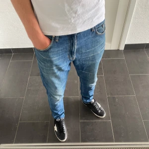 Tiger of Sweden jeans - Säljer ett par blå Tiger of Sweden Pistolero jeans i klassisk femficksmodell. Jeansen har en rak passform med snygga slitningar och kontrastsömmar. Tillverkade i bomull och perfekta för dig som gillar en stilren och avslappnad look.