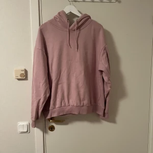 Ljusrosa hoodie från 157, storlek L - En ljusrosa hoodie från lager 157 i storlek L. Tröjan har huva med snörning och är tillverkad i mjuk bomullsblandning. Perfekt för chill dagar och har en enkel, clean look utan tryck eller mönster. Katt finns i hemmet 
