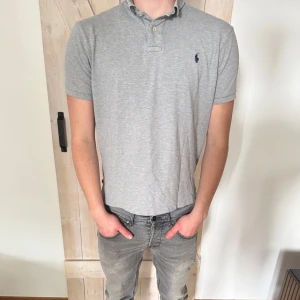 Grå pikétröja från Ralph Lauren - Snygg grå pikétröja från Ralph Lauren med klassisk krage och korta ärmar. Storleken är L men passar M. Skicket är bra.