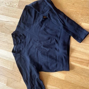 Svart ribbad långärmad tröja SOC - Svart långärmad träningströja från SOC (Stadium) i ribbat tyg. Tröjan är tillverkad i stretchigt material (polyamid och elastan) och har en tight och croppad passform. Hör av dig om du har frågor! 