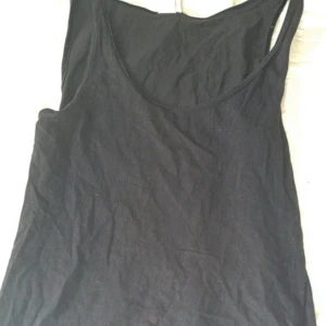 Svart linnetopp med breda axelband - Enkel svart linnetopp med breda axelband och rundad halsringning. Perfekt att matcha med jeans eller kjol för en clean look. Tunn och lätt, passar bra till varma dagar.