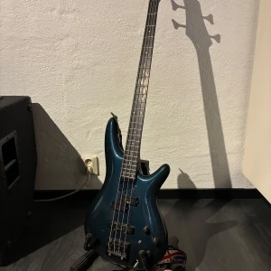 SoundGear Ibanez Elbas - Säljer nu min elbas då jag spelar alldeles för sällan.   Basen är en SoundGear av Ibanez. En riktigt fin bas som är tillverkad i Oktober 1987, av FujiGen Gakki i Japan.  Basen är i mycket bra skick och väldigt skön att spela.  Pris: 5000kr eller bud, föredrar snabb och smidig affär. Medföljer även två ljudsladdar, ett par plektrum, två vägghängare, stativet basen står på, remmen till basen samt en väska till basen. 