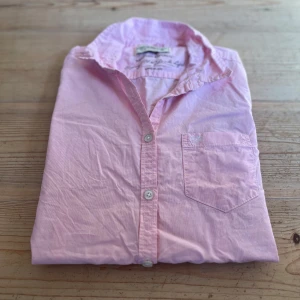 Rosa skjorta från Hampton Republic - Snygg rosa skjorta från Hampton Republic. Klassisk krage, bröstficka och knäppning framtill. Tillverkad i 100% bomull för en skön och luftig känsla. Fraktar inom 24h efter köp🚚.