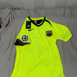 Barcelona Ronaldinho 10 Nike fotbollströja - Säljer en ikonisk Barcelona fotbollströja från Nike i neon-gul färg med svarta detaljer. Tröjan har korta ärmar, broderat klubbmärke, Champions League-märke på ärmen och Ronaldinho 10-tryck på ryggen. Tillverkad i lätt och ventilerande polyester. Är i storlek S men passar m också. Pris kan diskuteras 