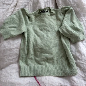 Ljusgrön stickad tröja  - Superfin ljusgrön stickad tröja med puffiga, halvlånga ärmar och ribbade muddar. Perfekt för dig som gillar en mjuk och mysig stil med lite volym på axlarna. Enkel att matcha med både jeans och kjol.