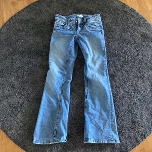 Blå bootcut jeans från Gina Tricot - Snygga ljusblå jeans från Gina Tricot i storlek 158. Modellen har bootcut-ben.  Jeansen är tillverkade i bomull och har en skön passform med normal midja. Använda 1 gång. 