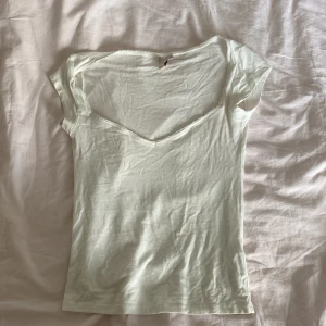 Vit v-ringad topp från Nelly XS - Säljer en enkel och fräsch vit topp från Nelly i storlek XS. Toppen har v-ringning med söt spetskant och korta ärmar. Den är figurnära och gjord i mjuk bomull, perfekt till jeans eller kjol. Superenkel att styla och passar året runt. Knappt använd 