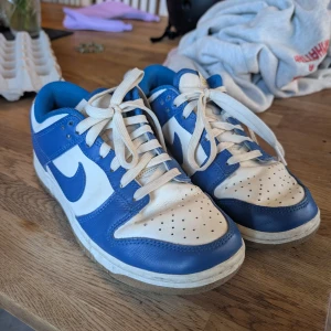 Nike Dunk Low blå/vita sneakers - Säljer ett par low nike dunks i blå och vit färg. Använda bara ett fåtal gånger, säljer för jag växt ur dem. Storlek 37,5 men de är lite små i storleken så snarare 37or. Köp sker via swish 🫶🏻