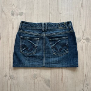 Blå lågmidjad jeanskjol  - Blå lågmidjad jeanskjol från Esprit i fint skick. Kan inte hitta storlek men skulle säga S, kanske passar M också. Tvärs över midjan är det 38 cm och den är ca 33 cm lång (längs med sidan). Använd gärna köp nu!
