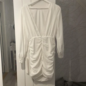 Vit klänning från NLY Trend - Supersnygg vit kortklänning från NLY Trend med djup v-ringning i ryggen, långa ärmar och dragkedja i sidan och är gjord i ett lätt, flowy material.