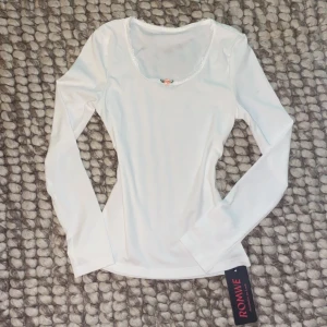 Vit långärmad topp med spets från Romwe - Supersöt vit långärmad topp från Romwe med ribbad struktur, spetskantad urringning och en liten rosa ros framtill. Helt oanvänd! ‼️Står S men skulle säga att det passar som en xs. Fråga om mått och funderingar.💓