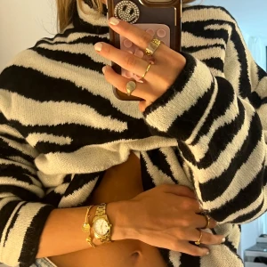 Oversized zebramönstrad stickad tröja - Säljer en oversized stickad tröja med svartvitt zebramönster och hög krage. Tröjan har långa ärmar och är supermjuk och skön, perfekt för att sticka ut lite extra. Passar dig som gillar djurmönster och vill ha en chill, trendig vibe.