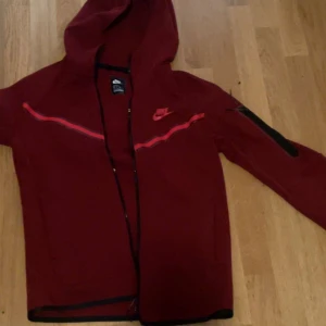 Vinröda mjukisbyxor från Nike - Snygga vinröda mjukisbyxor från Nike med svart snörning i midjan och klassisk Nike-logga på låret. Byxorna har en avslappnad passform och är perfekta för chill eller träning. Tillverkade i mjukt bomullsmaterial för extra komfort. Priset kan diskuteras;)