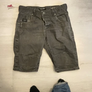 Grå jeansshorts från Jack & Jones - Snygga grå jeansshorts från Jack & Jones med klassisk femficksdesign och tydliga sömmar. Modellen är loose fit och har normal midja. Perfekta för en avslappnad stil under varmare dagar. Materialet är slitstarkt denim och shortsen har knapp och dragkedja framtill.