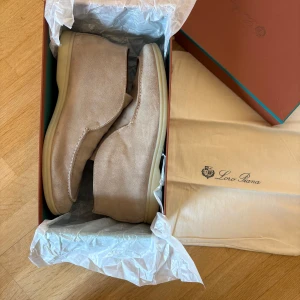 Beiga mocka loafers från Loro Piana - As schyssta beiga höga loafers från Lorro P. Låda och tillbehör medkommer. Skorna är strl 46 men passar bäst 45 och även 44.