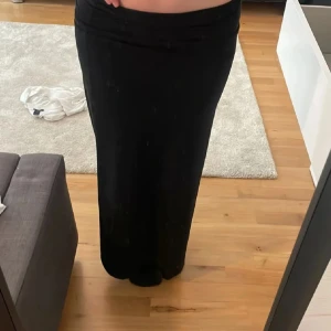 Svart långkjol från Gina Tricot - Säljer en svart långkjol från Gina Tricot. Kjolen har en enkel och stilren design med rak passform och resår i midjan. Perfekt att styla med crop top eller stickad tröja.