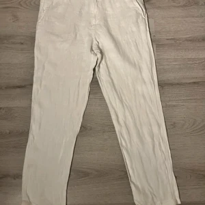  linnebyxor med normal passform - Snygga  linnebyxor med raka ben och klassisk design. Byxorna har fickor i sidorna och stängs med dragkedja och knapp. Perfekta för varmare dagar och ger en avslappnad men stilren look.