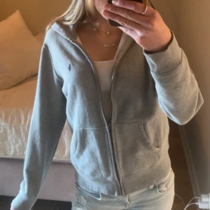 Grå hoodie med dragkedja från Ralph Lauren - Mysig grå hoodie från Ralph Lauren med dragkedja framtill och klassisk logga på bröstet. Tröjan har huva och fickor. Skriv för mer information eller bilder 💞