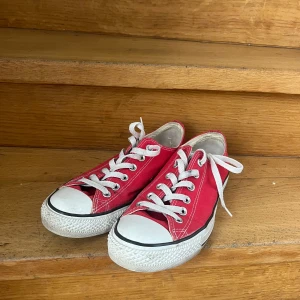 Röda låga Converse  - Klassiska röda Converse All Star sneakers med vit sula och vita snören. Låg modell med rund tå och platt sula. Pris kan diskuteras 