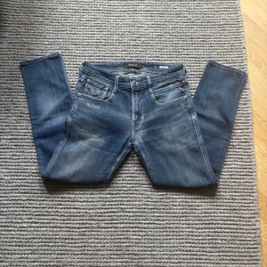 Replay Anbass  - Replay Anbass med små slitningar och en snygg wash. Tyvärr är själva lappen där storleken står bortklippt men måtten är 93 cm i längd och 37x2 cm i midjemått vilket då motsvarar L 30 w 30! Sitter slim!