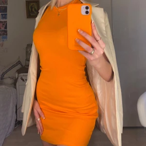 Orange ribbad kortklänning - Säljer en snygg orange ribbad kortklänning med tight passform och ärmlös design. Klänningen har en rund halsringning och perfekt nu till sommaren. Superenkel att styla med en kavaj eller sneakers 🧡