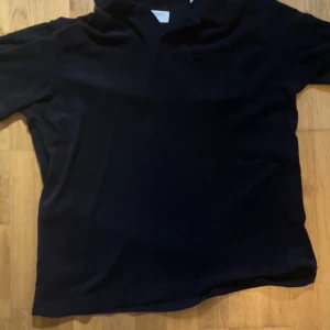 Svart frotté piké - En enkel svart piké med krage. Perfekt för en stilren och avslappnad look. Storlek L. Pris kan diskuteras vid snabb affär! 