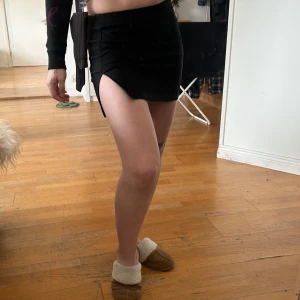 Mini kjol - Snygg kort kjol med en slits. Aldrig använt. Har en dragkedja på sidan