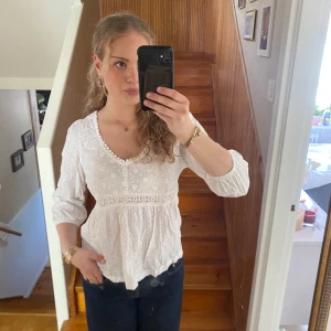 Vit broderad blus - Vit broderad blus från affär i Spanien. Blusen har långa ärmar och v- ringning. Blusen är aldrig använd och är därför i nyskick 