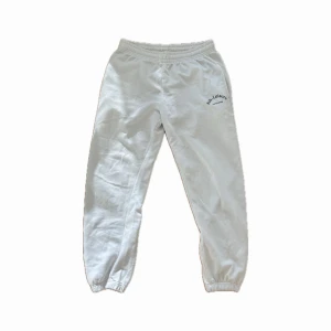 Vita mjukisbyxor från Boohoo - Vita mjukisbyxor med resår i midjan och vid bensluten. Byxorna har en enkel design med en liten logga på ena sidan framtill. Perfekta för en avslappnad stil. Skriv för frågor eller om pris🫶