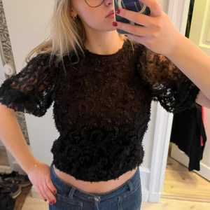 Svart spetsblus - Säljer en svart croppad blus blommiga spetsdetaljer. Knytning i nacken. Köpt på Kappahl för ca 4 år sen till en julafton och sen inte blivit använd mer. Chic och classy. 