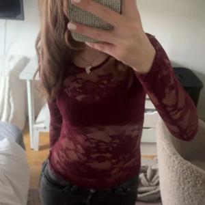 Vinröd spetsblus med lång ärm - Säljer en vinröd, transparent spetsblus med lång ärm och rund halsringning. Blusen har ett blommigt spetsmönster och är figurnära i passformen. Perfekt att styla med ett linne eller bh under för en trendig look. Den är strl xs men har inte så mycket stretch och blir för tajt för mig runt bysten tyvärr därför säljer jag den, skriv om ni har några frågor använd en gång på min födelsedag på kvällen