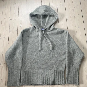 Grå stickad hoodie från Zara - Mysig grå stickad hoodie från Zara med ribbade muddar och bred ribbad nederkant. Tröjan har huva med snören så man kan reglera storlek på huvan och är perfekt för kyligare dagar. Enkel och stilren design som passar till mycket.