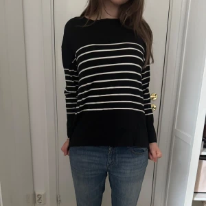 Svart och vit randig tröja - Säljer en svart långärmad tröja med vita horisontella ränder. Tröjan har en avslappnad passform och rund halsringning. Perfekt till jeans för en enkel och stilren look.