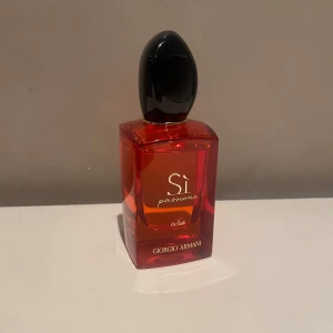 Sì Passione Éclat Eau de Parfum 50ml - Säljer en lyxig parfym från Giorgio Armani, Sì Passione Éclat. Flaskan är elegant i röd glas med svart lock och rymmer 50 ml. Har använt ca 5 ml av den