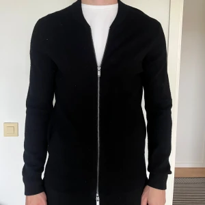 Svart kofta från Massimo dutti - Stilren svart cardigan jacka med hel dragkedja framtill. Jackan har lång ärm och en enkel, clean design som passar till många olika outfits. .