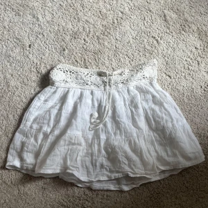 Vit kjol med virkade detaljer från Pull&Bear - Supersöt vit linne kortkjol från Pull&Bear med bred virkad midja och knytband. Den är liten i storleken.🩷