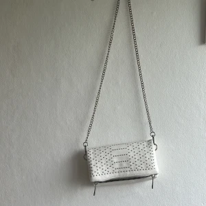 Vit axelväska med nitar från Even&Odd - Säljer en vit axelväska frå  Even&Odd med silverfärgade nitar. är jättefin använt några gånger💕