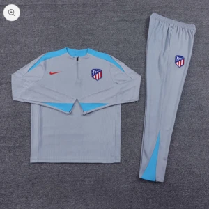 Grå långärmad Atlético Madrid fotbollströja och byxa - Säljer en grå långärmad fotbollströja och matchande byxa från Nike med Atlético Madrid-logga. Tröjan har ljusblå detaljer vid axlar och ärmslut samt röd Nike-logga. Byxan har samma ljusblå detalj och klubbmärke.