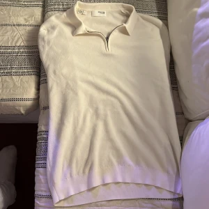 Vit pikétröja med dragkedja från Selected Homme - Säljer en stilren vit pikétröja från Selected Homme i storlek L, aldrig använd! Tröjan har dragkedja vid halsen och är tillverkad i ett mjukt material som känns bekvämt mot huden. Perfekt för en clean och fräsch look inför sommaren!