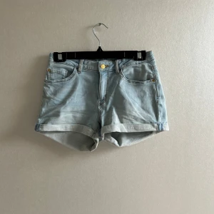 Ljusblå jeansshorts  - Stretchiga ljusblåa jeansshorts med klassisk femficksdesign och uppvikta benslut. Gylf med knapp och dragkedja. Finns resår på insidan för att kunna justera midjemåttet. Perfekta för varma dagar och enkel att matcha med olika toppar💗💗