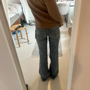 Lågmidjade blåa bootcut jeans från med broderad ficka - Säljer mina absoluta favorit jeans som tyvärr blivit för små. Köpta här på plick och då var dom nya med prislapp, har själv använt dem mycket men har bara haft dem i cirka 1 år och det finns inga defekter. Köpte dom för 380 kr. Midjemåttet är 34 cm, innerbenslängden är 83 cm. Det är storlek W27 L33. Första och sista bilderna är lånade. 