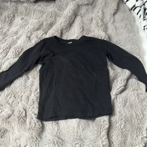 Svart långärmad bomullströja från 157 - En enkel svart långärmad tröja från 157 i 100% bomull. Perfekt basplagg med rund hals och rak passform. Passar till det mesta och är riktigt skön att ha på sig.