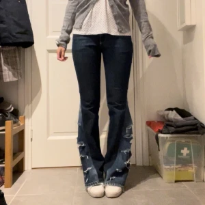 Mörkblå bootcut jeans med slitningar - Mörkblå jeans med bootcut-modell och tydliga slitningar nertill på benen. Byxorna har klassiska fickor bak och fram samt kontrastsömmar. Perfekta för dig som gillar en lite mer edgy stil. Jag är 160 för referens!