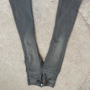 Grå jeansbyxor från LAB Industries - Säljer ett par grå jeansbyxor från LAB Industries med klassisk femficksdesign och normal passform. Byxorna har dragkedja och knapp framtill samt bälteshällor. Perfekta till en avslappnad stil.