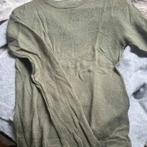 Olivgrön tunn stickad tröja - Säljer en olivgrön, tunn och lätt stickad tröja med rund halsringning och långa ärmar. Väldigt tunn och skön, perfekt nu till sommaren. Endast använd en gång så den är i bra skick! Hör av er vid frågor 🥰