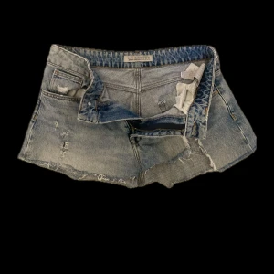 Ljusblå jeanskjol från Zara - Säljer ett par ljusblå jeanskjol från Zara med råa kanter och slitna detaljer. Klassisk femficksmodell med knapp och dragkedja framtill. Perfekta för sommardagar och enkel att matcha med allt. Den är väldigt kort 