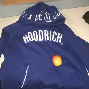 Blå hoodie från Hoodrich - Säljer en blå hoodie från Hoodrich med stor vit logga på bröstet och tryck på huvan. Hoodien har känguruficka framtill och textdetaljer på fickan. Perfekt för en avslappnad streetwear-look. Och byxor, äpple på köpet khoya❤️på gud ni ska inte få äpplet på köpet bara för ni inte vill köpa snabbt 